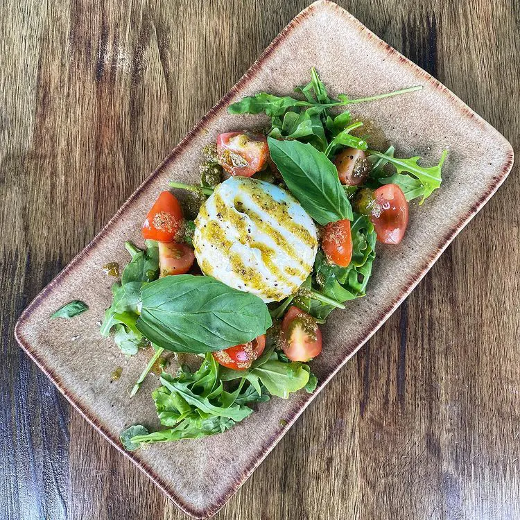 burrata dressed in pesto Genovese on fresh rocket and cherry tomatoes 