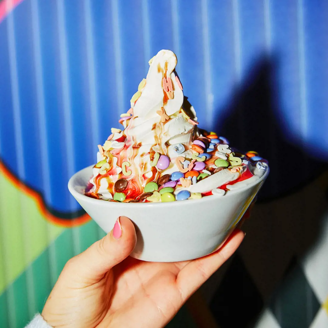 Ice cream is topped with multicoloured sweets and sauces.