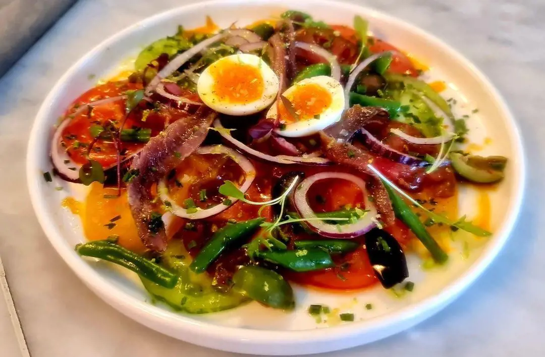 Tomato salad with brown anchovies, quail eggs, green beans and black olives